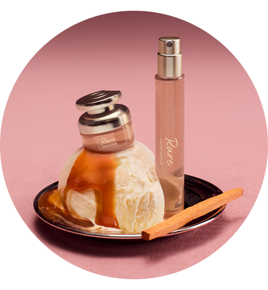 Perfume bottle with ice cream and a cinnamon stick on a pink background