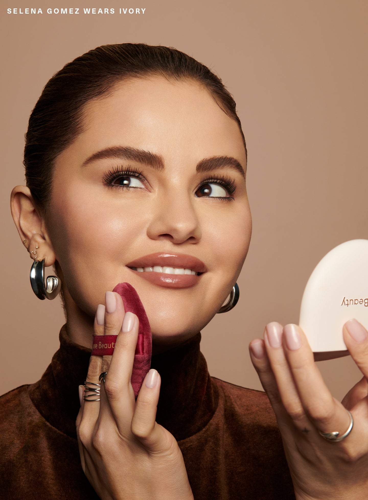 Selena Gomez applying Rare Beauty's True to Myself Pressed Finishing Powder in the shade Ivory with the Soft Touch Powder Puff.