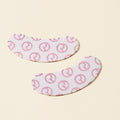 Rare Beauty's Find Comfort Hydrating Under Eye Patches covered with the Rare Beauty logo laying on a soft yellow surface.