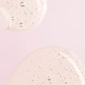 A close-up of Rare Beauty's Find Comfort Gentle Exfoliating Body Wash against a soft pink background.