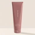 Rare Beauty's Find Comfort Gentle Exfoliating Body Wash standing on a white surface against a white background.