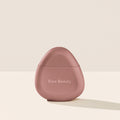 Rare Beauty's Find Comfort Hydrating Hand Cream standing on a white table against a white background.