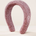 Rare Beauty's Find Comfort Headband sitting on a white surface against a white background.