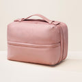 Rare Beauty's Puffy Toiletry Bag in the shade Mauve on a white table against a white background.