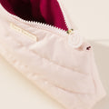 The Puffy Makeup Bag by Rare Beauty is shown open to display the roomy, sultry berry inside lining.